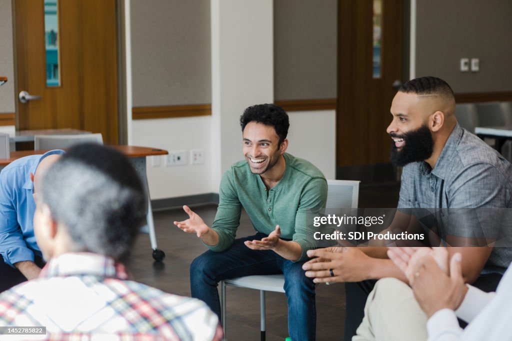 Young man gestures and laughs with support group