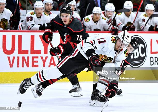 Taylor Raddysh of the Chicago Blackhawks battles Sebastian Aho of the Carolina Hurricanes for the puck during the second period of their game at PNC...