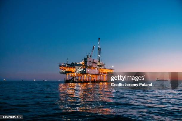 beautiful dusk sky over an offshore oil drilling close to huntington beach - zee stockfoto's en -beelden