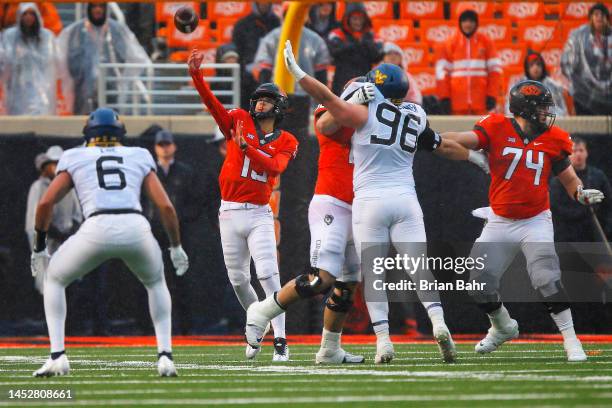 Quarterback Garret Rangel of the Oklahoma State Cowboys throws under pressure from linebacker Exree Loe and defensive lineman Edward Vesterinen of...