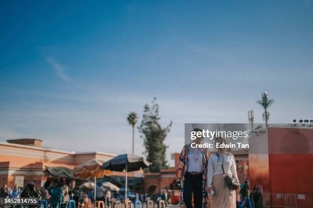 asian chinese female tourist walking together at djemaa el fna square, marrakech, morocco during sunset - medina district stock pictures, royalty-free photos & images