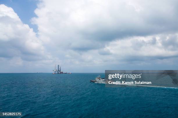 a warship is patrolling the sea with oil rig platform background view from aerial - military rescue stock pictures, royalty-free photos & images