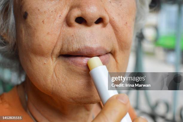 senior woman using a lip balm - cream mouth stock pictures, royalty-free photos & images