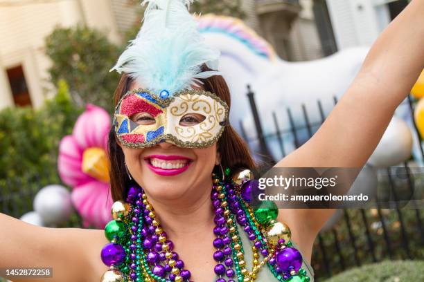 a young latin tourist female, wearing mask, costumes and necklaces celebrating mardi gras through the streets in new orleans. - mardi gras float stock pictures, royalty-free photos & images