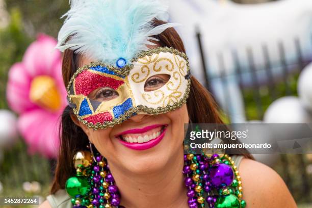 a young latin tourist female, wearing mask, costumes and necklaces celebrating mardi gras through the streets in new orleans. - new orleans people stock pictures, royalty-free photos & images
