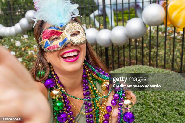 a young latin tourist female, wearing mask, costumes and necklaces celebrating mardi gras through the streets while taking a selfie with her cellphone in new orleans. - mardi gras float stock pictures, royalty-free photos & images