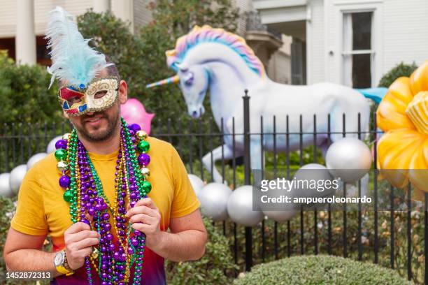 a young latin tourist male, wearing mask, costumes and necklaces celebrating mardi gras through the streets in new orleans. - mardi gras float stock pictures, royalty-free photos & images