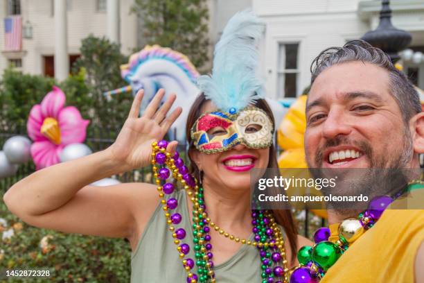 happy latin tourists friends / heterosexual couple celebrating mardi gras in new orleans dressing necklace and masks while taking a selfie. - mardi gras float stock pictures, royalty-free photos & images