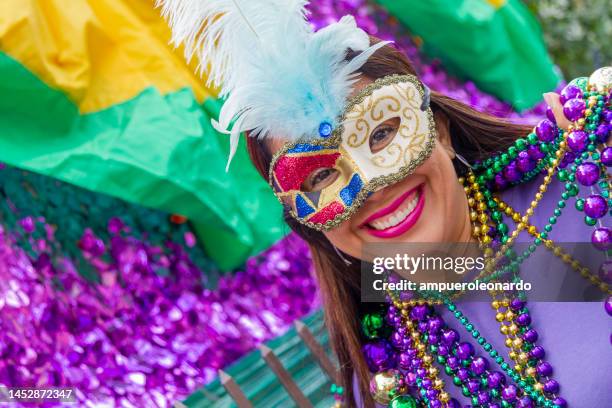 eine junge lateinamerikanische touristin, die maske, kostüme und halsketten trägt und mardi gras durch die straßen von new orleans feiert. - festwagen stock-fotos und bilder