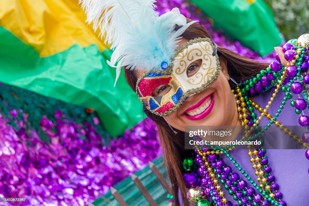 Uma jovem turista latina, usando máscara, fantasias e colares celebrando o Mardi Gras pelas ruas de Nova Orleans.