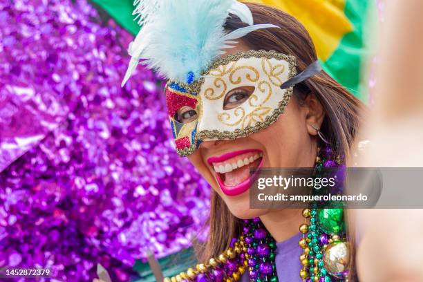 a young latin tourist female, wearing mask, costumes and necklaces celebrating mardi gras through the streets while taking a selfie with her cellphone in new orleans. - mardis gras stock pictures, royalty-free photos & images