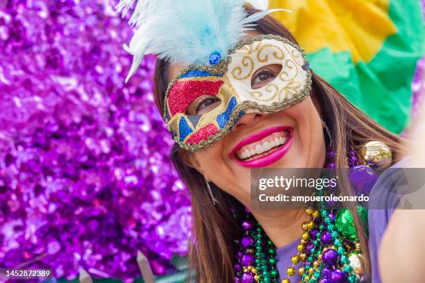 a young latin tourist female, wearing mask, costumes and necklaces celebrating mardi gras through the streets while taking a selfie with her cellphone in new orleans. - mardi gras float stock pictures, royalty-free photos & images