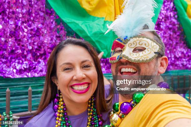 happy latin tourists friends / heterosexual couple celebrating mardi gras in new orleans dressing necklace and masks while taking a selfie. - mardi gras float stock pictures, royalty-free photos & images