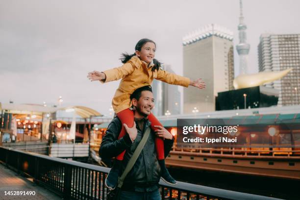 father giving daughter shoulder ride by tokyo canal in winter - japan winter stock pictures, royalty-free photos & images