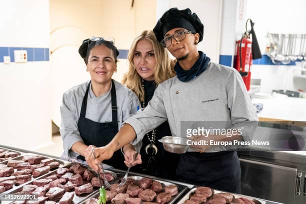 Journalist Cristina Tarrega poses with two volunteers during the celebration of a solidarity meal at the Jose Maria de Llanos Foundation on December...