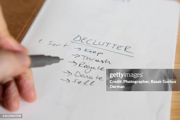 a person taking declutter notes on a paper (list; keep, recycle, thrash, donate, sell) - entrümpeln stock-fotos und bilder