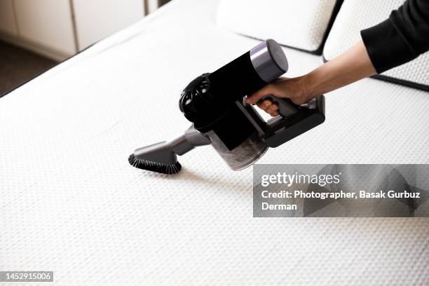 a woman vacuuming the mattress - matras stockfoto's en -beelden