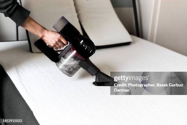 a woman vacuuming the mattress - aspirapolvere foto e immagini stock