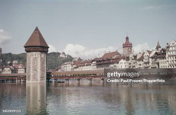 View of the Swiss city of Lucerne with the Kapellbrucke wooden footbridge over the River Reuss and the Wasserturm tower in the middle of the river...