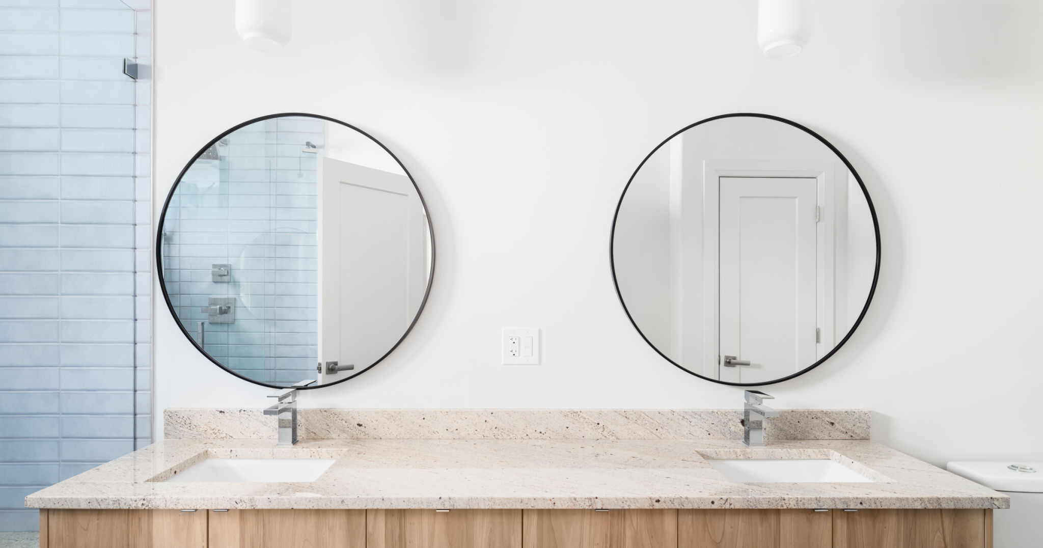A bathroom with a wood cabinet and circular mirrors. A bathroom with a wood cabinet and circular mirrors.