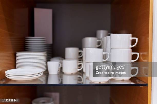 photograph of a small group of white porcelain tableware, clean and tidy on a kitchen shelf. - pires imagens e fotografias de stock