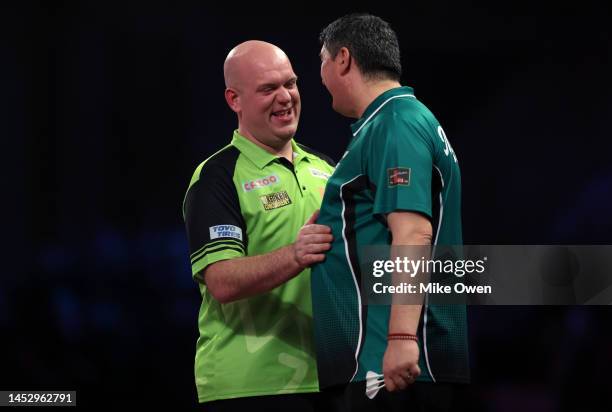 Michael van Gerwen of Netherlands and Mensur Suljovic of Serbia shake hands following their Third Round match during Day Nine of The Cazoo World...