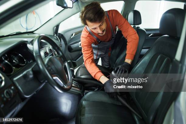 young handsome man vacuuming car seats - car detailing stock pictures, royalty-free photos & images