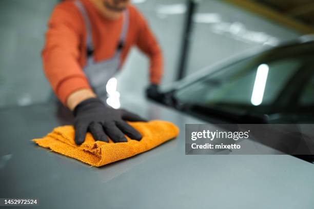 nahaufnahme eines nicht erkennbaren professionellen auto-detailers, der die motorhaube mit einem mikrofaser-handtuch reinigt - mikrofaser stock-fotos und bilder
