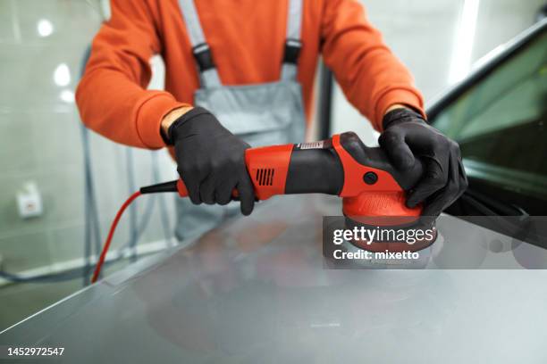 primer plano de un detallista irreconocible puliendo el capó del coche con una máquina pulidora rotativa - abrillantar fotografías e imágenes de stock