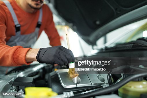 Close up shot of professional car detailer cleaning car engine space with a brush