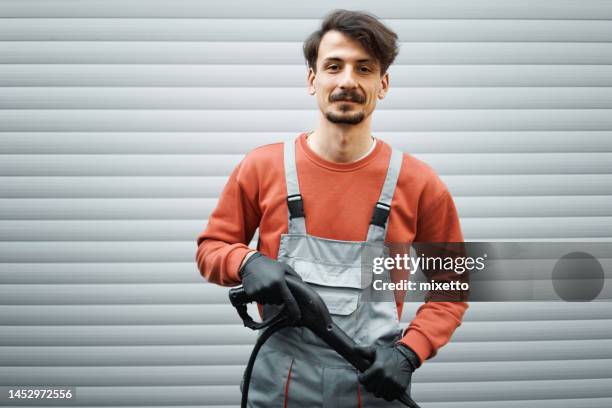 retrato do detalhador profissional do carro segurando a arma da lavadora de pressão na frente de sua garagem - high pressure cleaning - fotografias e filmes do acervo