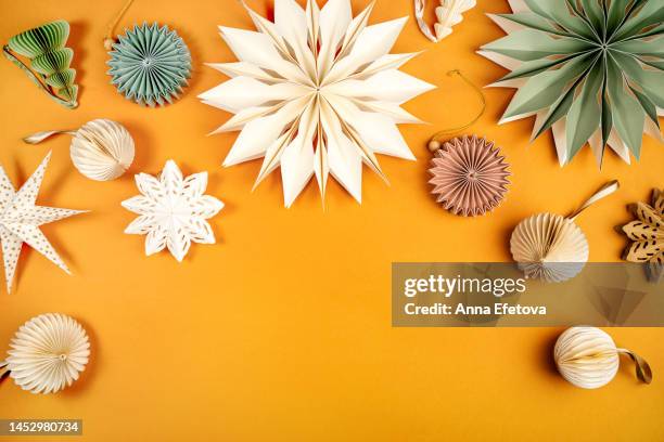 paper snowflakes and christmas tree ornaments in festive composition on orange background. merry christmas and a happy new year concept - christmas origami fotografías e imágenes de stock