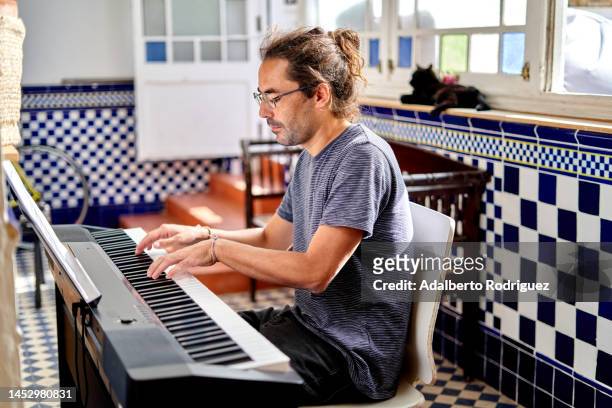 focused man playing electric piano at home - banknoten stockfoto's en -beelden