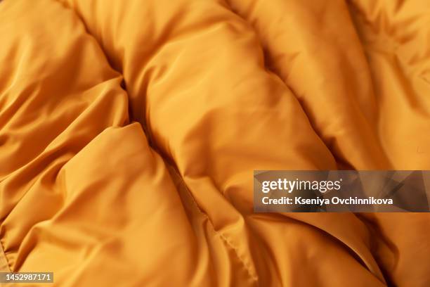 down jacket fabric background, orange puffer jacket texture - down feather stock pictures, royalty-free photos & images