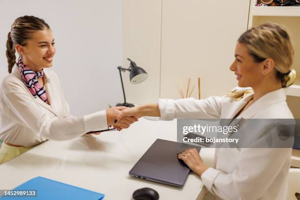 travel agent hand shaking with satisfied female client at travel agency - malta business stock pictures, royalty-free photos & images