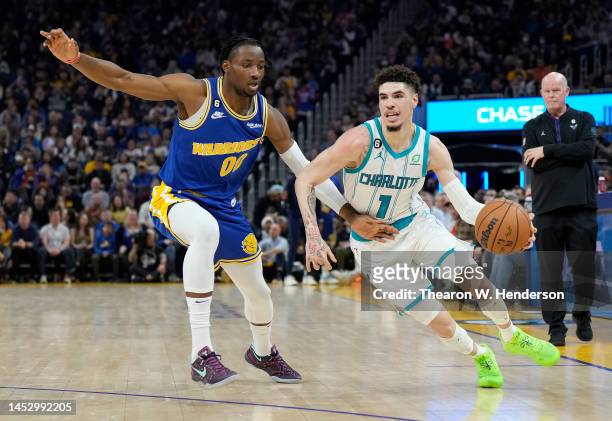 LaMelo Ball of the Charlotte Hornets dribbles the ball while closely defended by Jonathan Kuminga of the Golden State Warriors during the first...