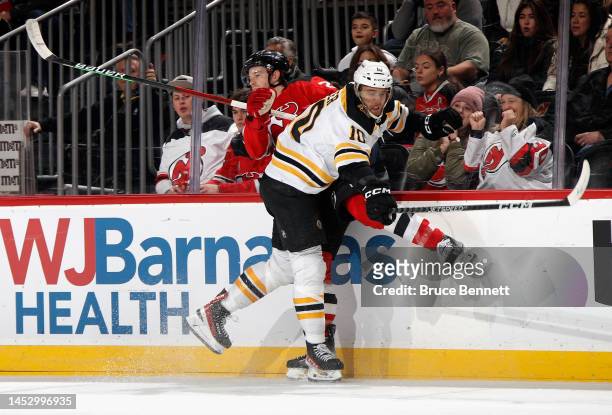 Greer of the Boston Bruins checks Damon Severson of the New Jersey Devils during the first period at the Prudential Center on December 28, 2022 in...