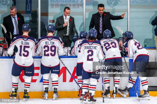 Members of the Tri-City Americans surround head coach Stu Barnes and associate coach T.J. Millar to discuss strategy during a second period stoppage...