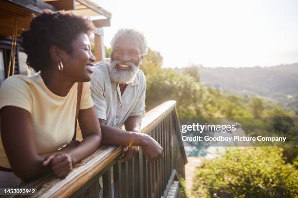 豪華なバケーションレンタルのバルコニーに立つ笑う夫婦 - older couple travelling ストックフォトと画像