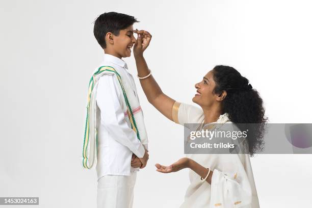 south indian mother applying tilaka to forehead of her son - south indian ethnicity stock pictures, royalty-free photos & images