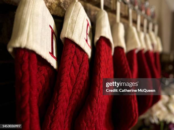 long row of classic red christmas stockings hanging over brick fireplace - damstrumpor bildbanksfoton och bilder