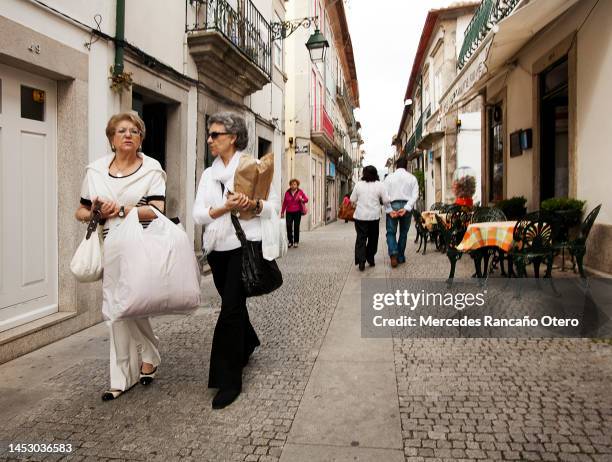 senior women holding bags, walking down the street. - viana do castelo district stockfoto's en -beelden