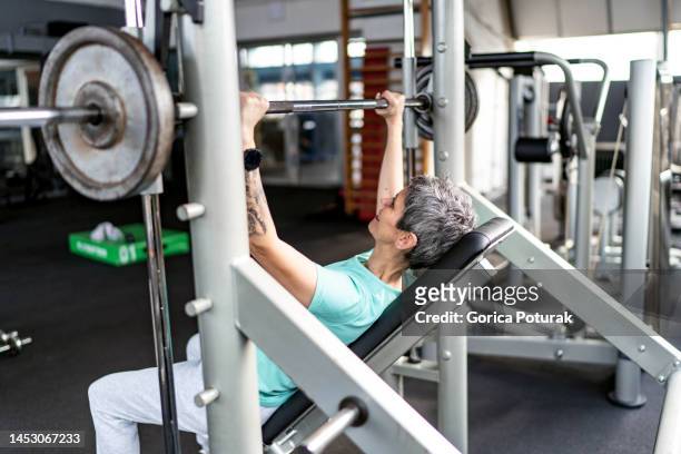 portrait of a happy mature woman working out with weights at gym - weightlifting stock pictures, royalty-free photos & images