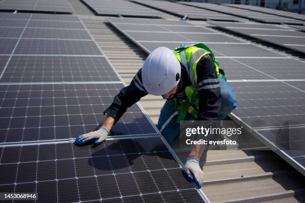 blue collar worker install solar panel on rooftop. - técnica de fotografia imagens e fotografias de stock