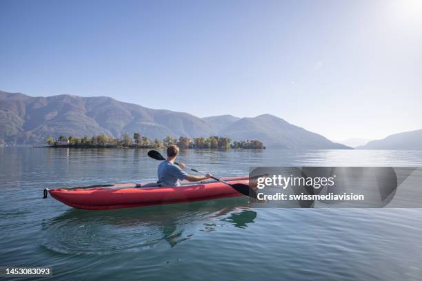 uomo in canoa su un lago - andare in canoa foto e immagini stock