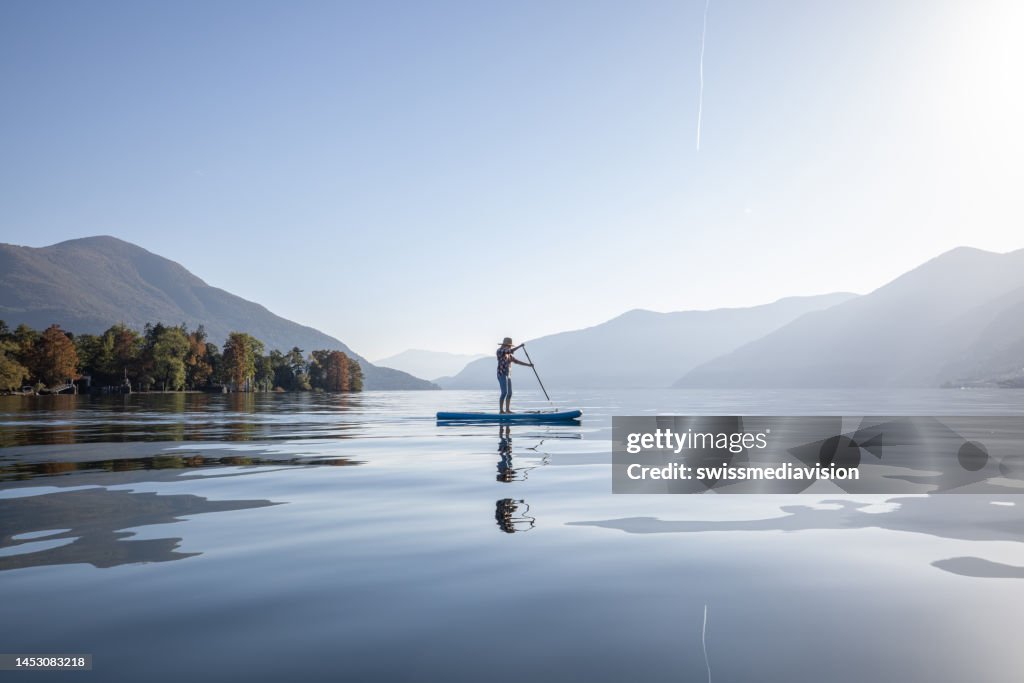 Mujer de pie remando en un lago