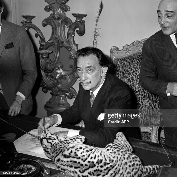 Spanish artist Salvador Dali signs his book "Lettre ouverte a Savador Dali" at his publisher, on May 12 as his Colombian ocelot Babou lies on the...
