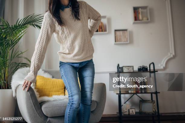 woman has back problems - standing on chair stockfoto's en -beelden