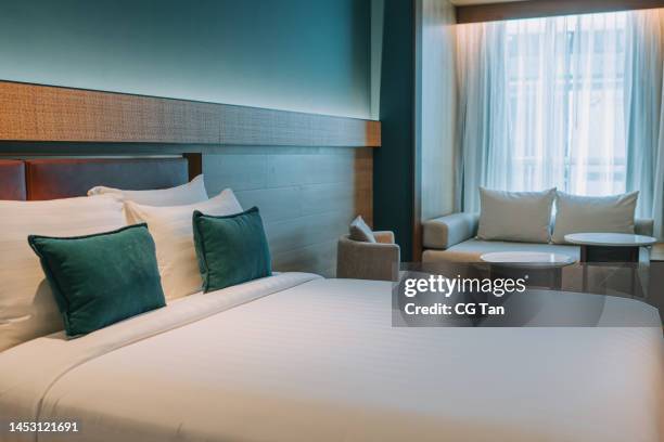 habitación moderna con cama doble, mesillas de noche y sofá cama de día - motel fotografías e imágenes de stock