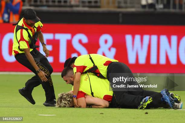 Security tackle a streaker after the the Men's Big Bash League match between the Perth Scorchers and the Melbourne Stars at Optus Stadium, on...